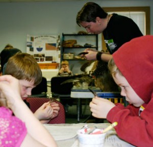 Students and teacher closely examining feathers.