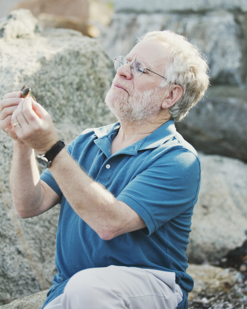 Man kneeling by rocks inspecting something in his hand.