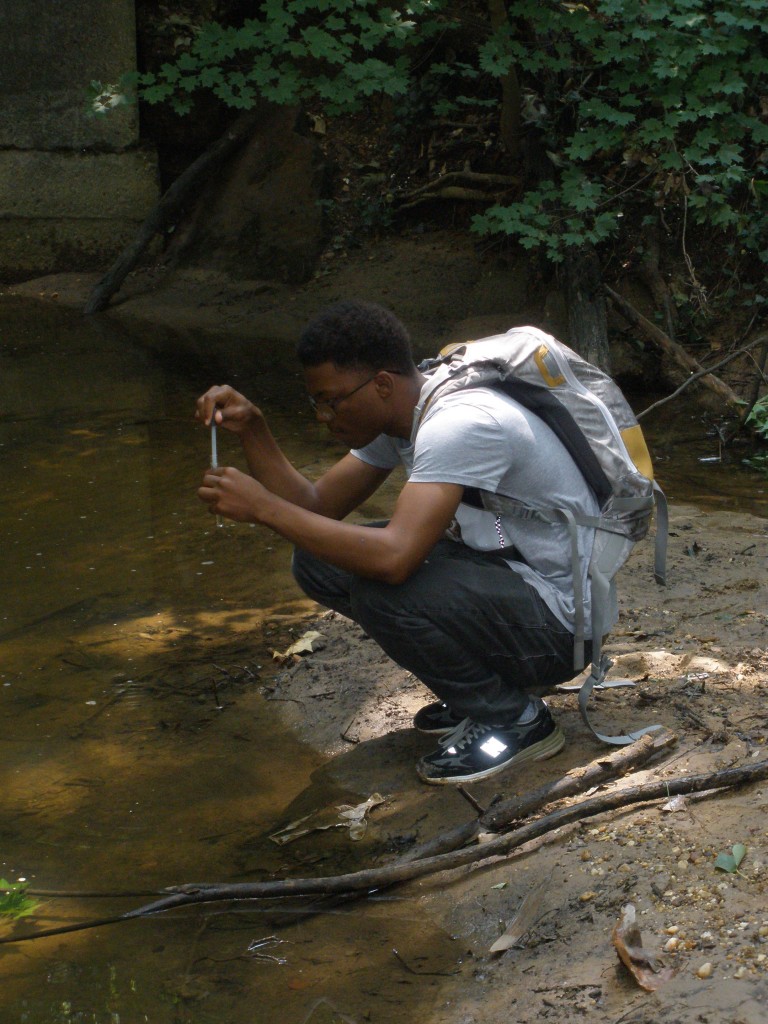 Kofi Henderson collects a water sample at Pope Branch of the Anacostia River.