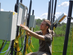 Joe Dawson kneels by a control box on marsh