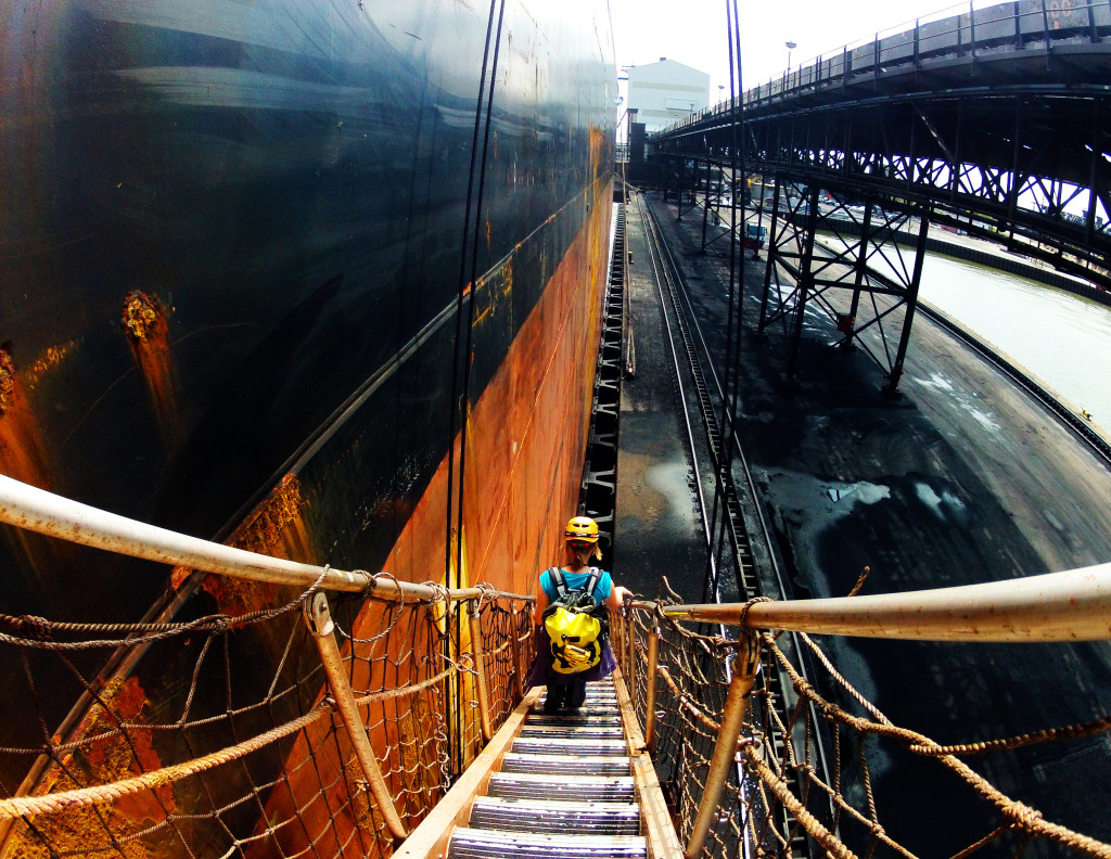 Woman descends gangway of large cargo ship.