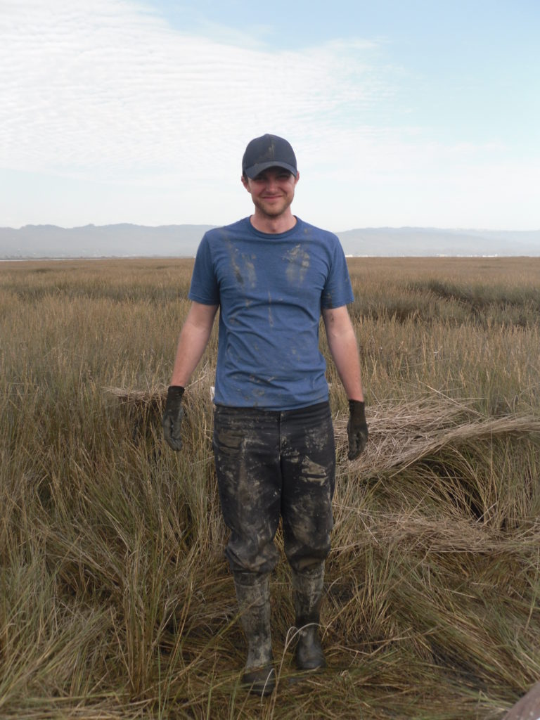 Man with muddy clothes in grassy wetland