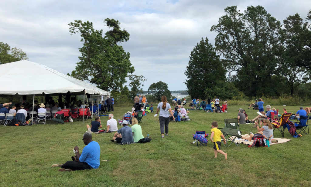 Overlook of Rhode River, with families on grass and white tent with musicians