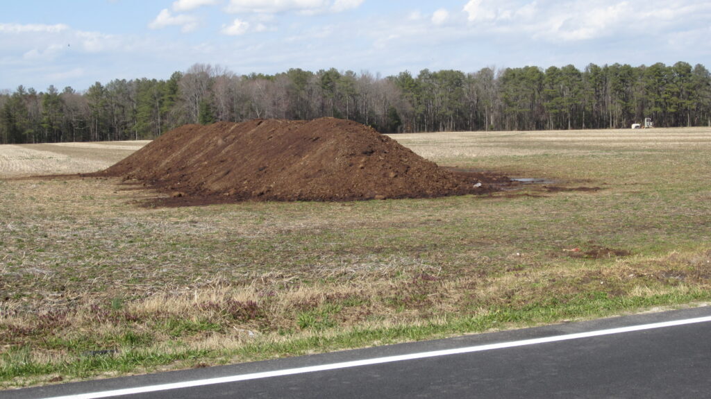 Pile of brown manure in a field by a roadside