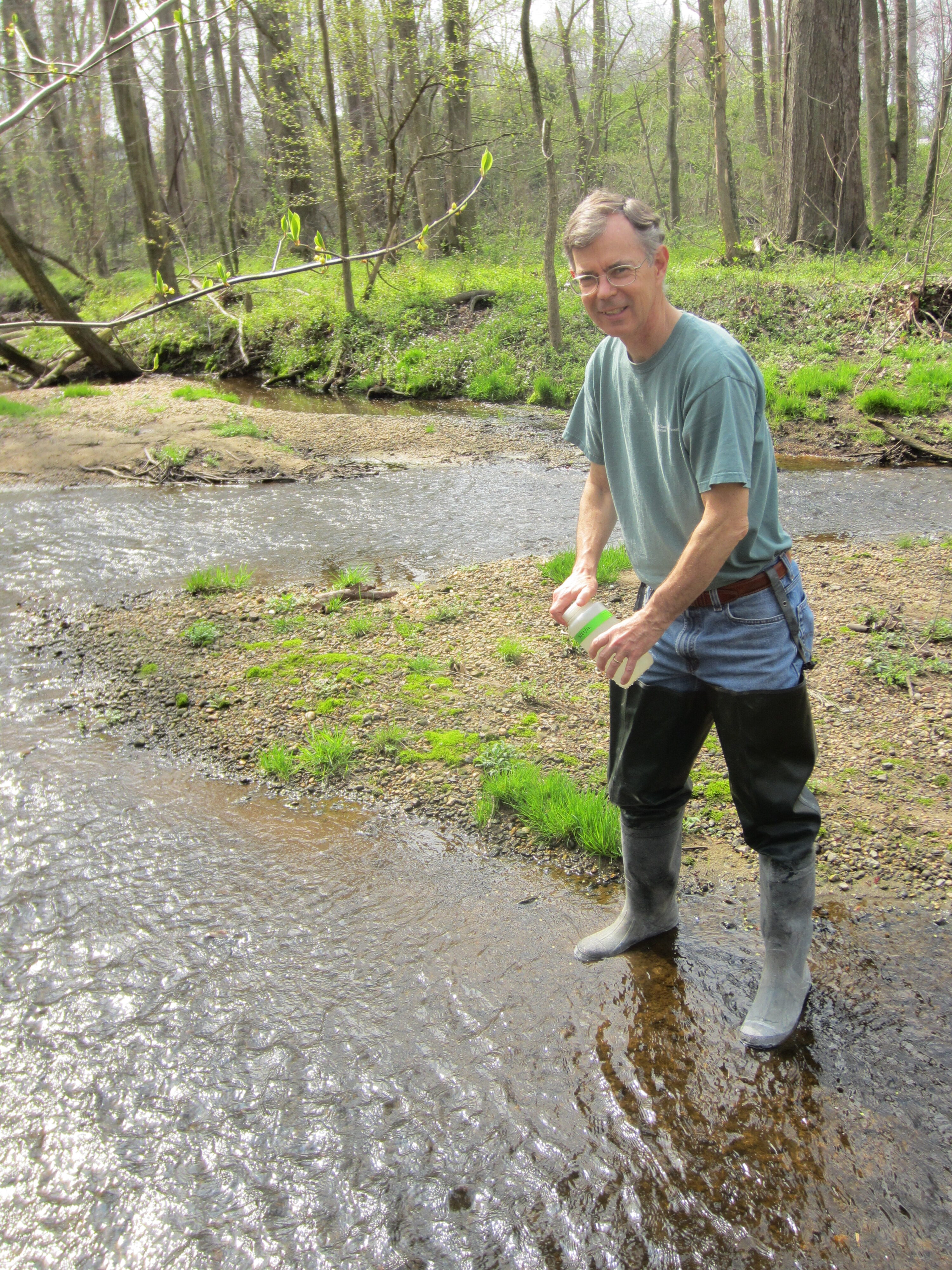 Man in high boots standing in stream.