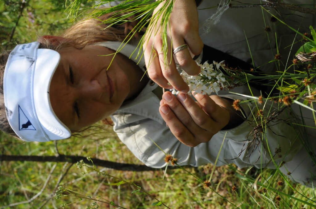 Young woman in visor examining a white flower