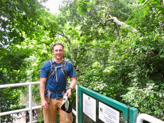 Man on a metal balcony, with a forest in the background