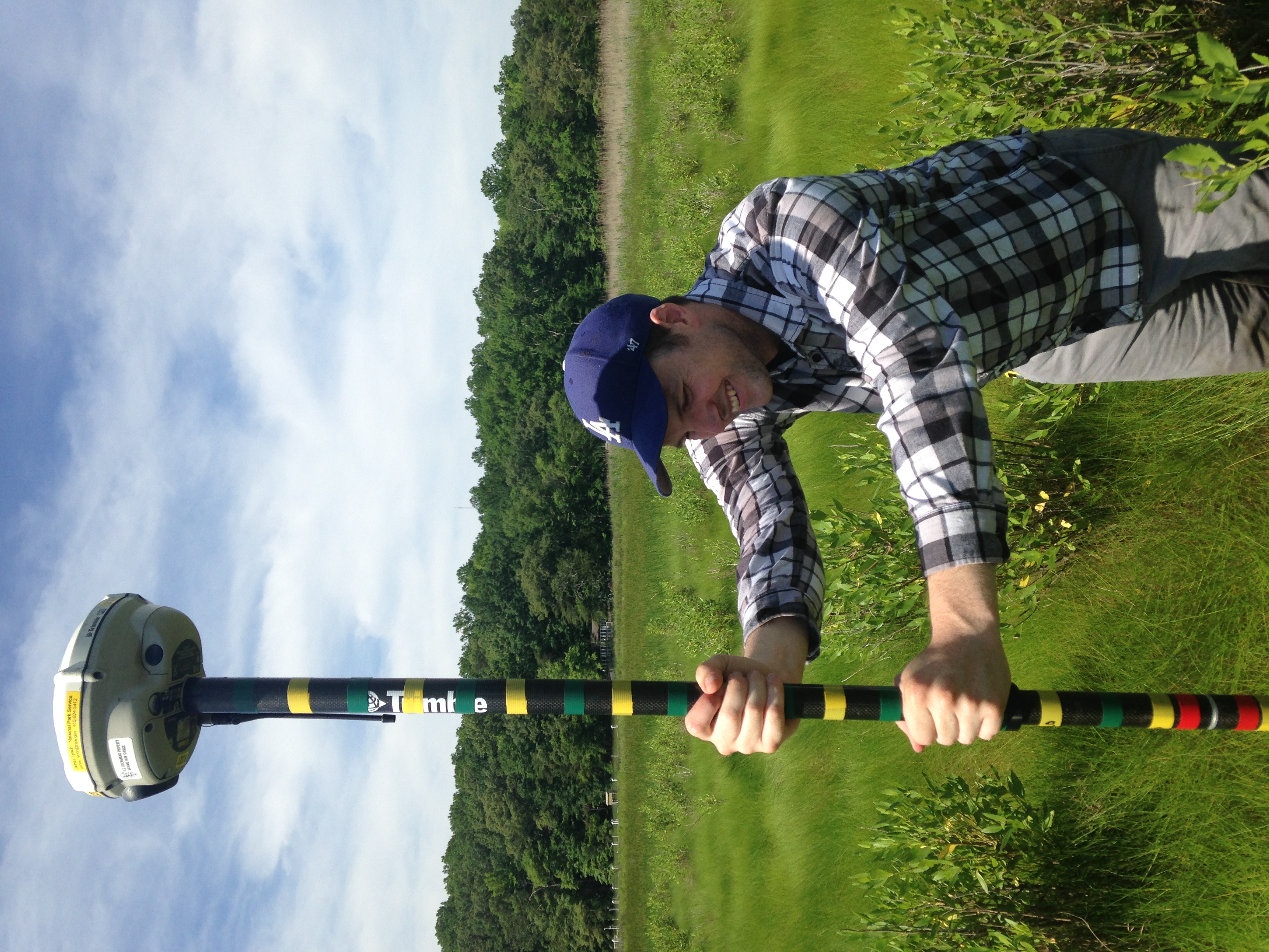 Man in wetland holding striped pole to measure elevation