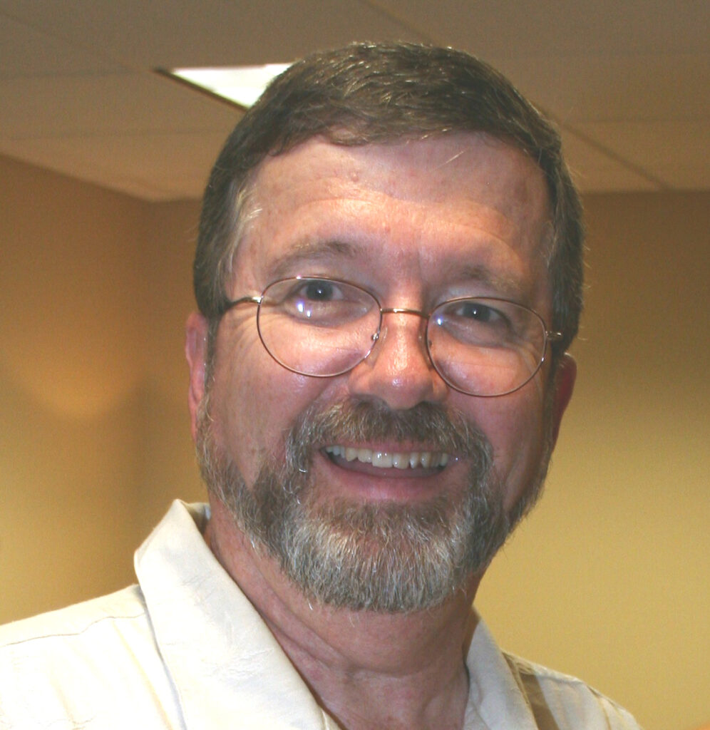 Head and shoulders picture of a scientist with brownish-gray hair, a beard and glasses