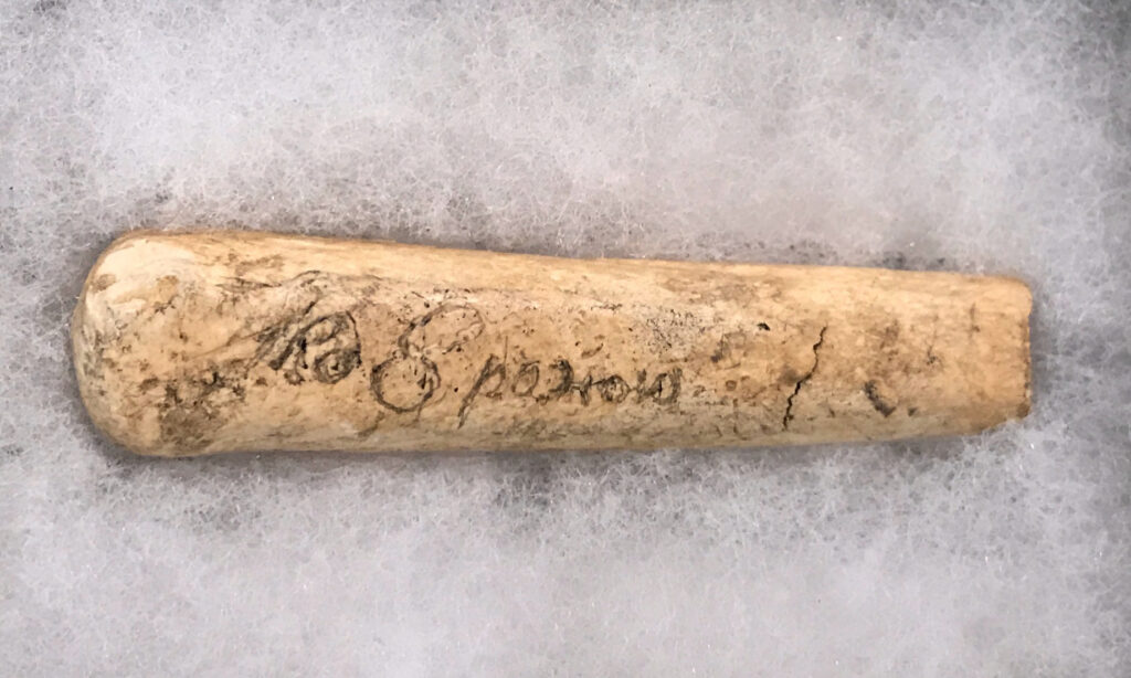 Cream-colored bone knife with a brown script engraving